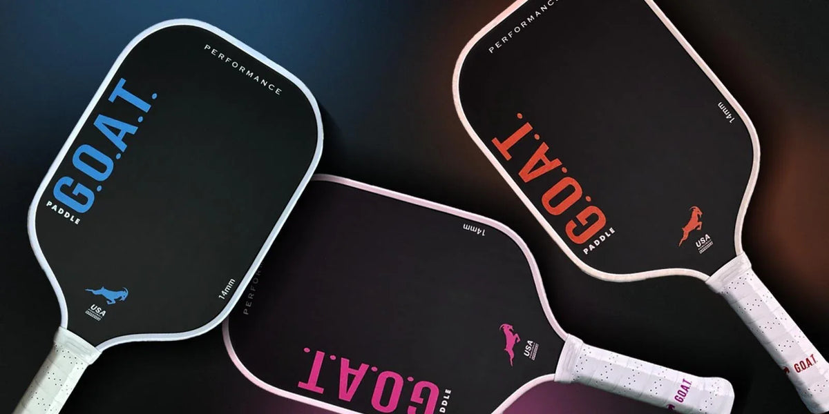 Three G.O.A.T. pickleball paddles in blue, red, and pink designs.