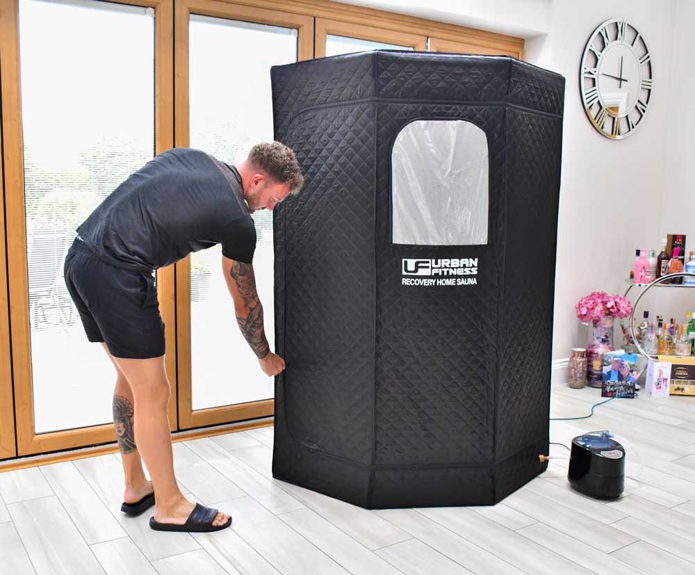 Man using Urban Fitness portable recovery home sauna indoors, next to large windows, Bassline Retail