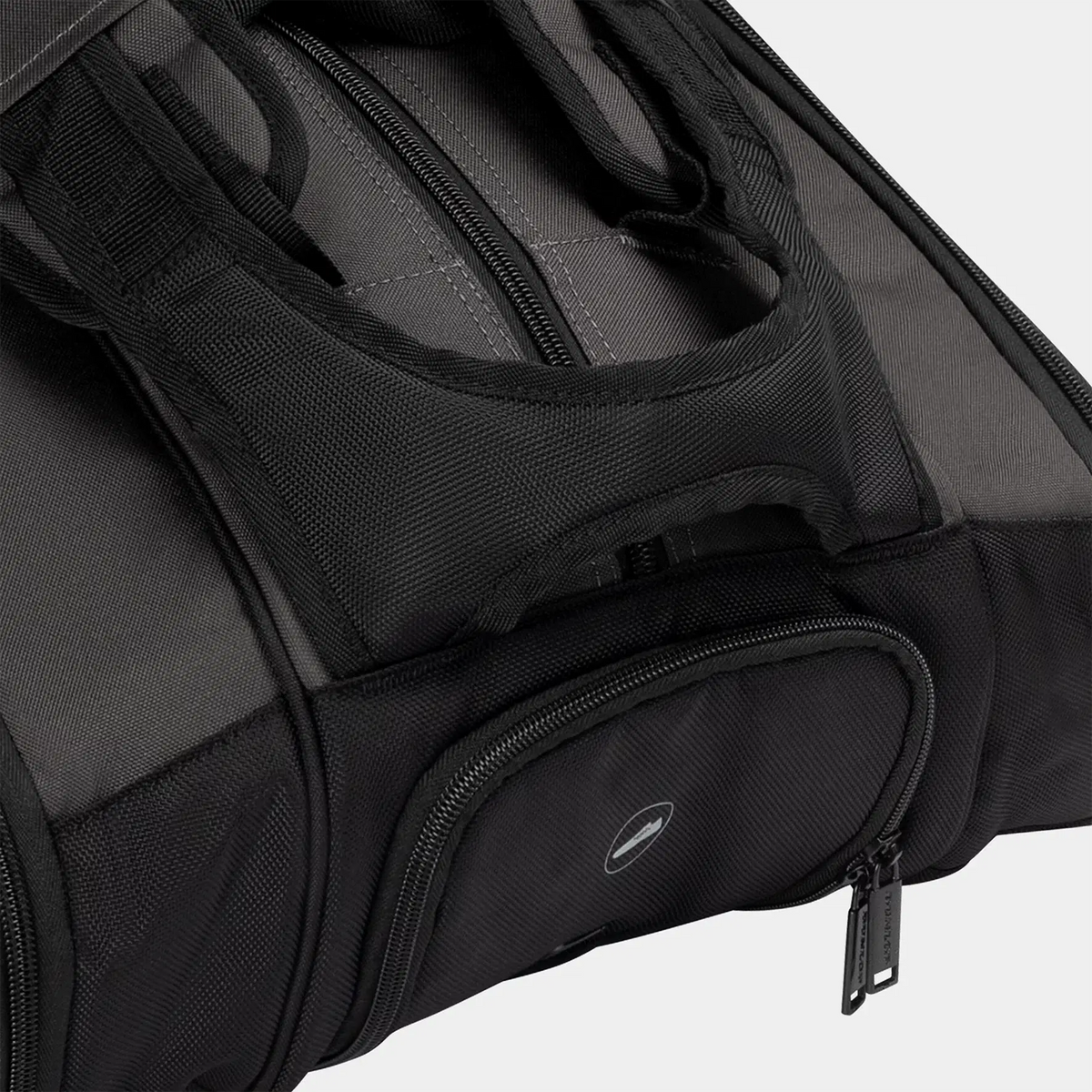 Close-up of a black durable sports equipment bag with padded handles and zippered compartments.